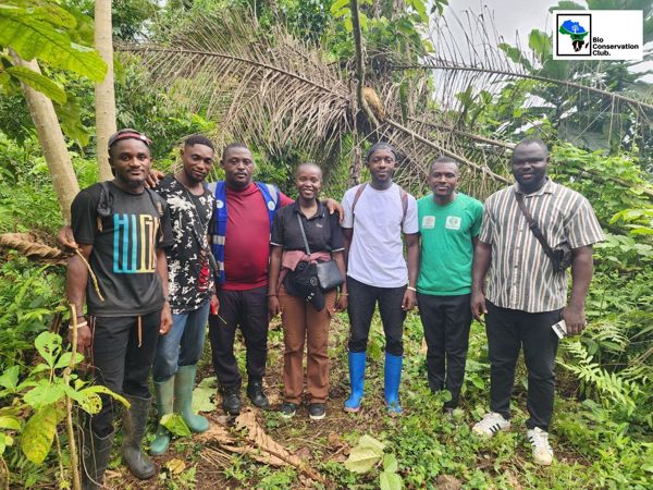 Seven field team members standing together in a green forest setting.