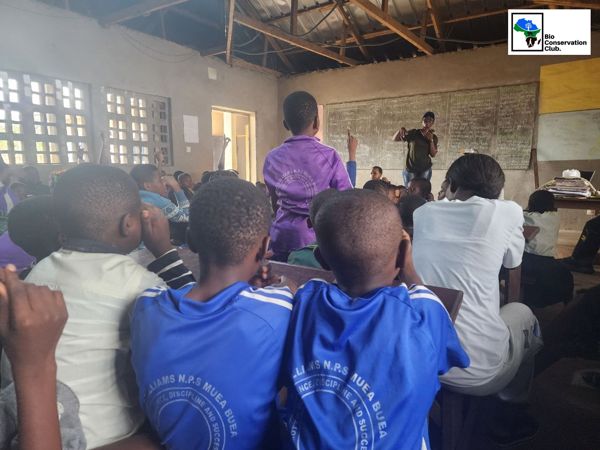 A student raising a hand during a classroom outreach session.