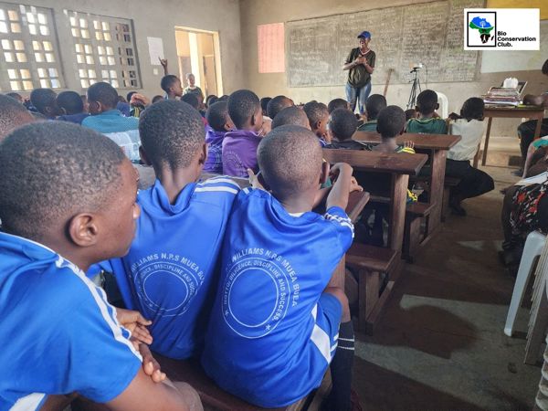 Students listening to a facilitator at the front of a classroom.